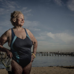 older woman in a swim suit standing in front of a pier
