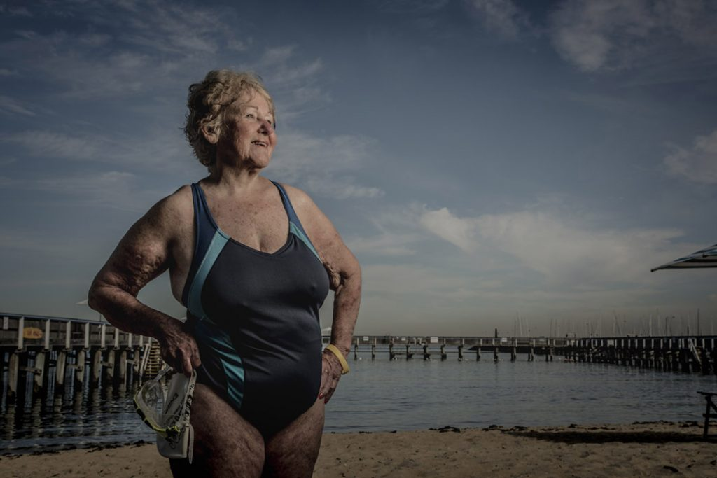 older woman in a swim suit standing in front of a pier